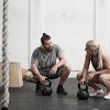 Couple with kettlebells in cross training gym Couple with kettlebells in cross training gym
